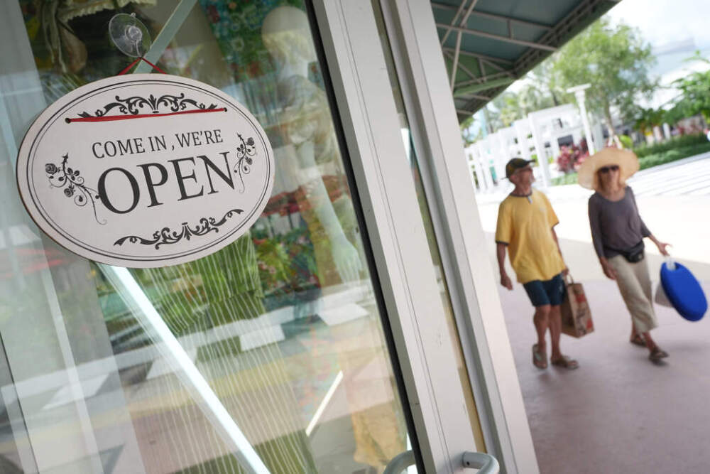 Shoppers walk by a clothing store in Miami Beach
